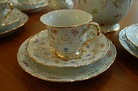  A close-up view of a coffee cup.  Every flower, every bit of gold trim is hand painted.